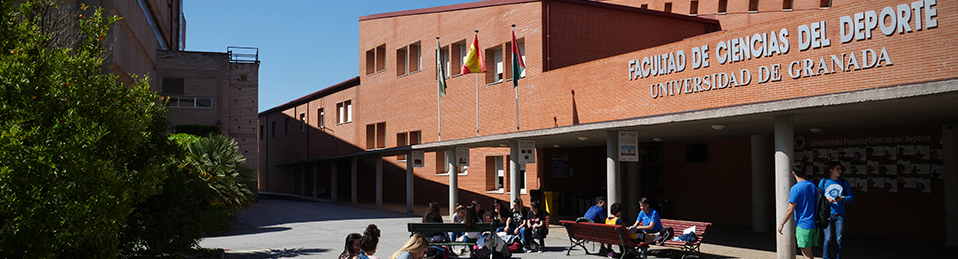 Vista de la entrada de la Facultad de Ciencias del Deporte, entorno abierto con bancos y estudiantes